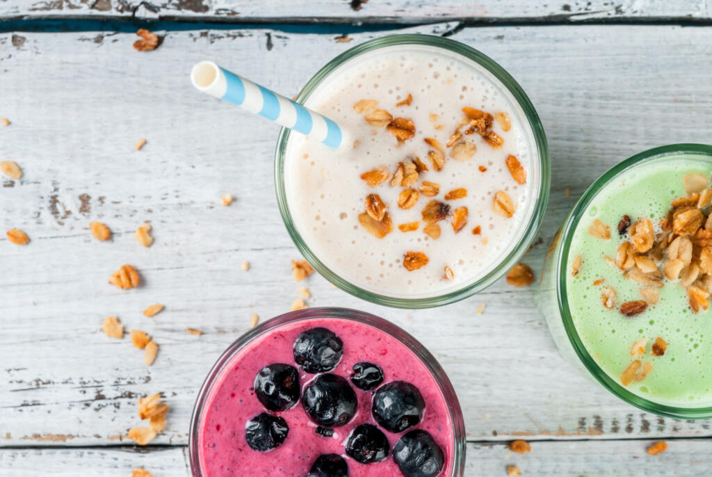 Close-up of three smoothies in glasses with straws