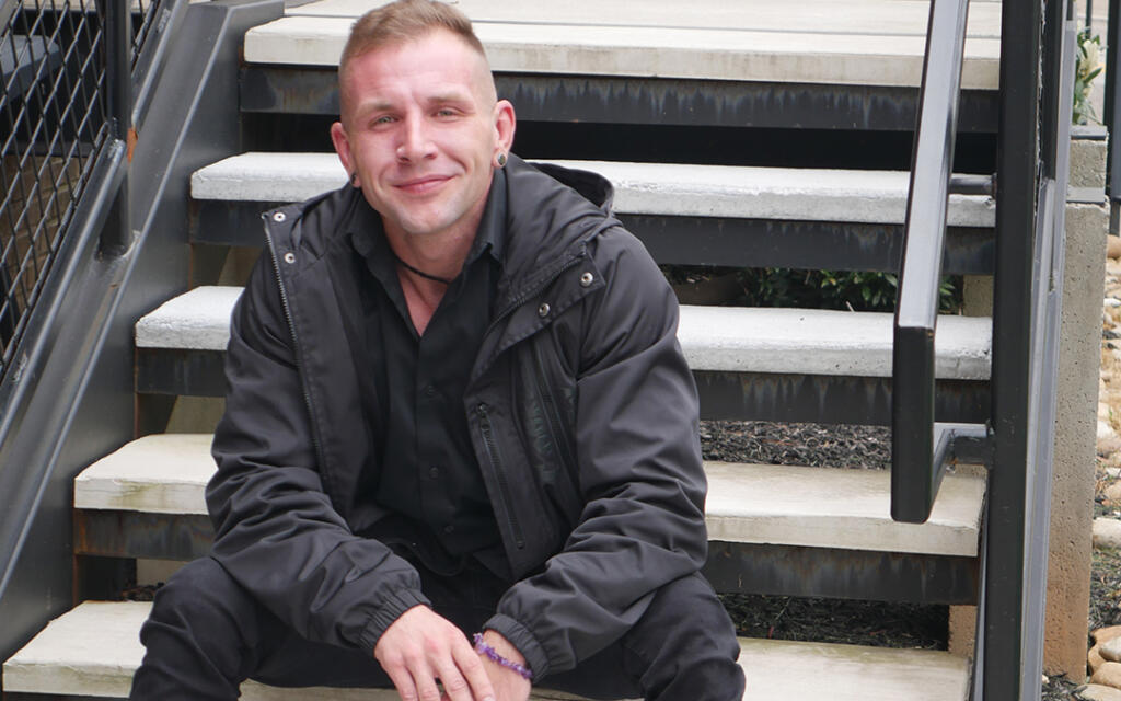 Man sitting on stairs outdoors smiling at camera