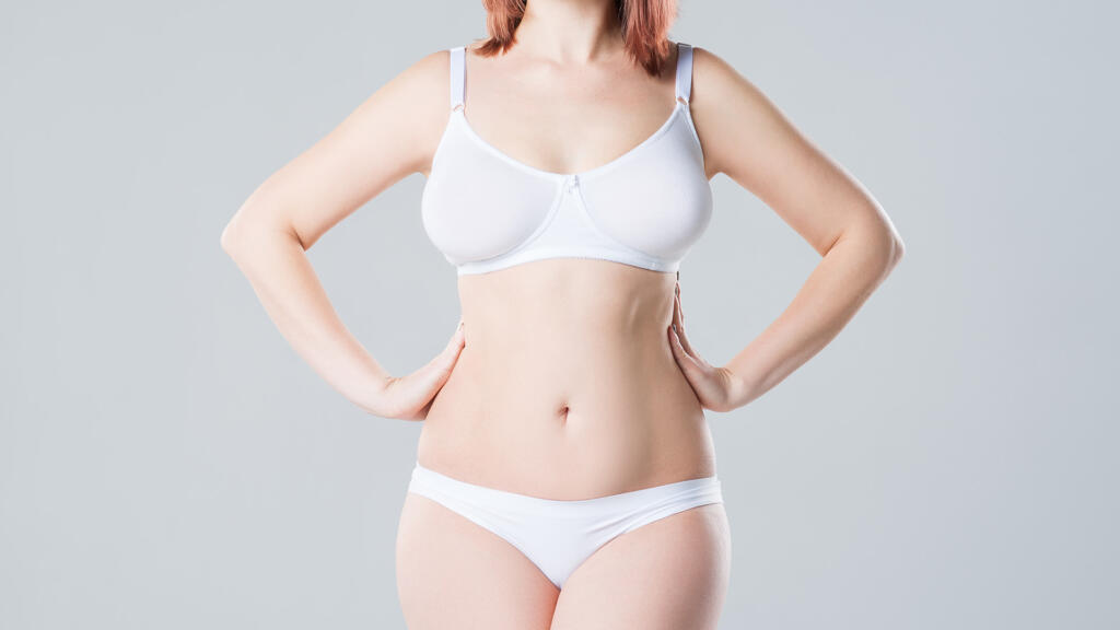 Woman in bra and underwear standing with hands on hips