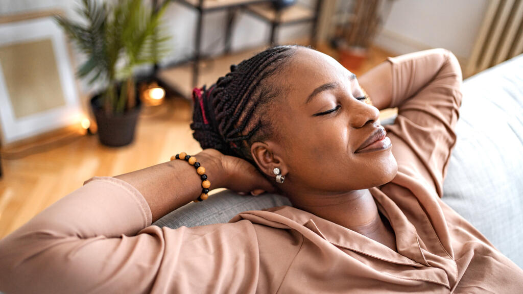 Woman leaning back on couch smiling after cosmetic surgery