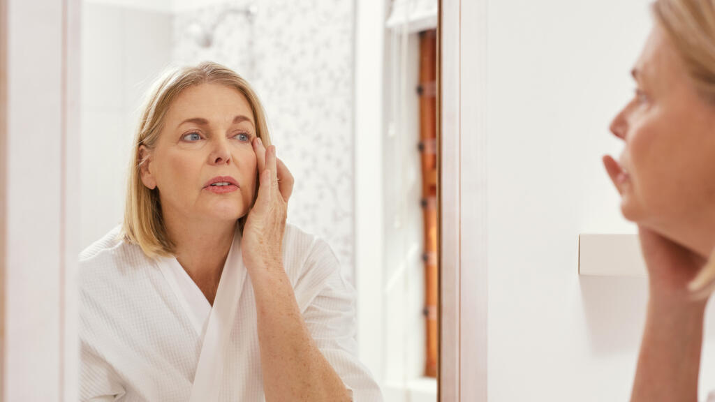 Woman looking in the mirror inspecting face
