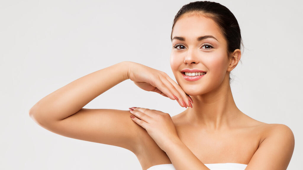 Woman smiling while raising arm and touching shoulder