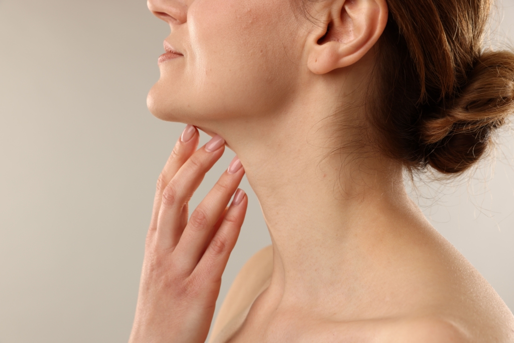 Woman touching her neck on light grey background, closeup.
