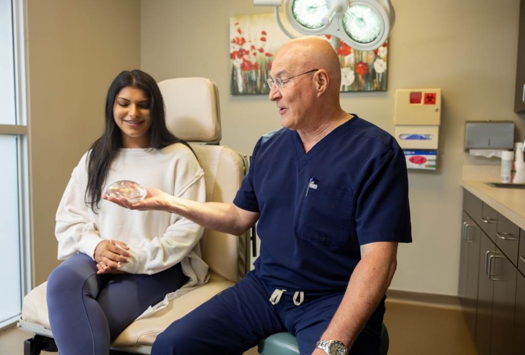 Dr. Jay Lucas showing a patient a breast implant sizer during a breast augmentation consultation at The Lucas Center in Knoxville